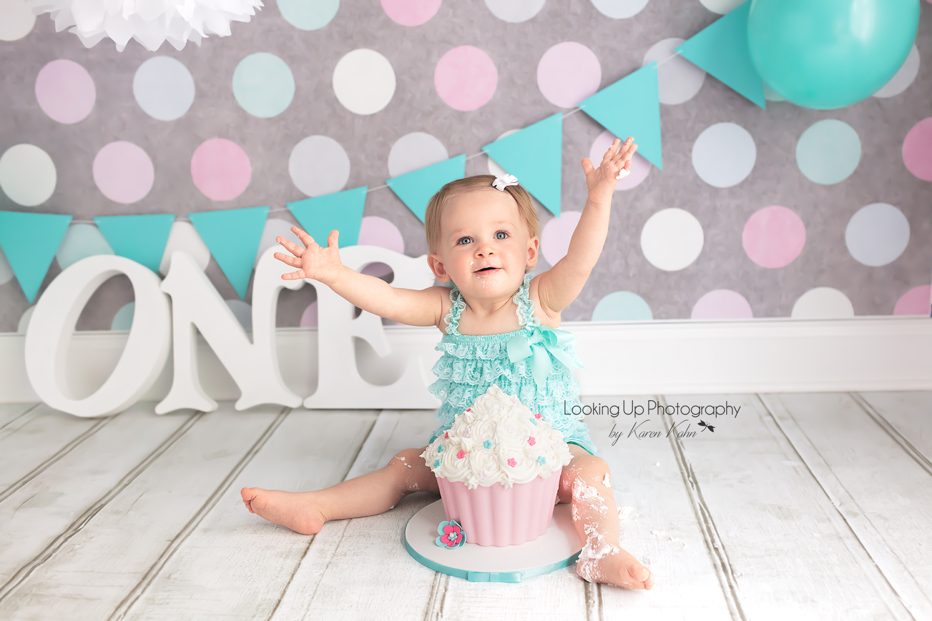 Green and pink themed cake smash session for one year old milestone baby girl looking sweet in lace with polka dots for 12 month portrait