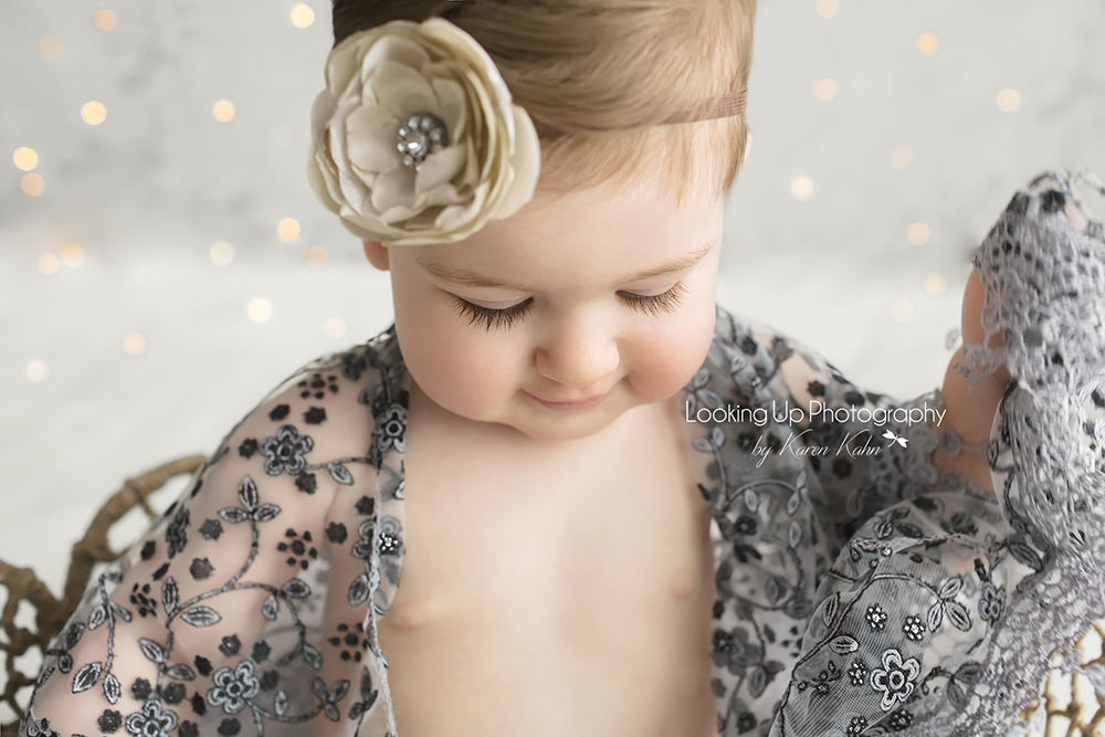 9 month old baby girl in gray lace and flower headband with sparkles for milestone portrait session