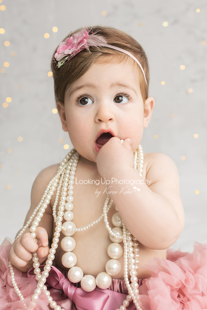 Baby girl adorned in pink tutu and white pearls with sparkles for 9 month milestone portrait session