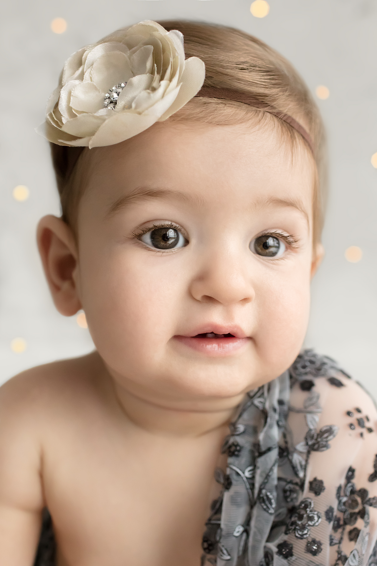9 month old baby girl in gray lace and flower headband with sparkles for baby milestone portrait session