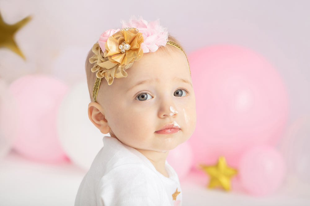 one year-old girl with gray eyes looking seriously at the camera, 1st birthday cake smash session