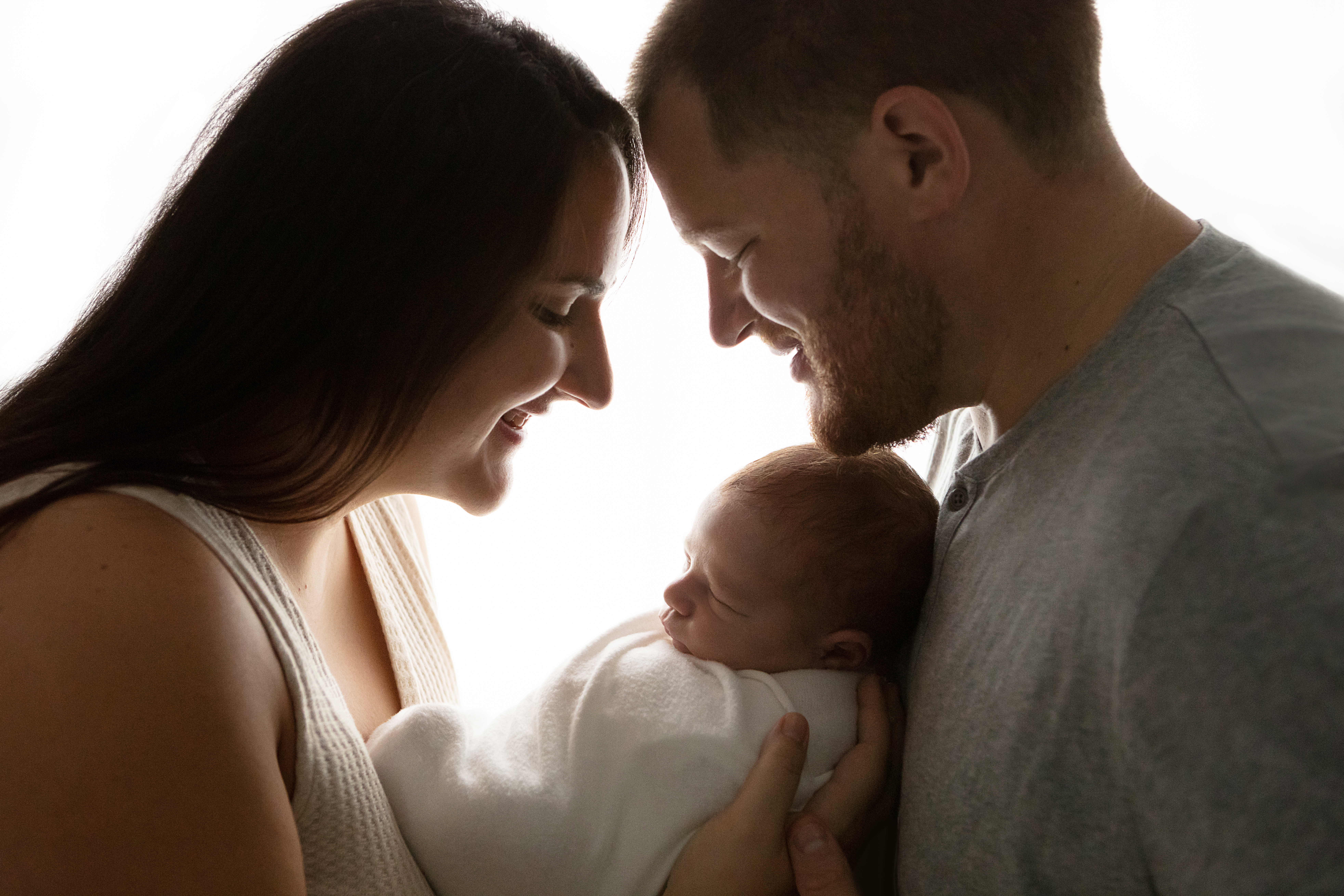 silhouette backlit image of a new family of three, mom, dad, baby boy