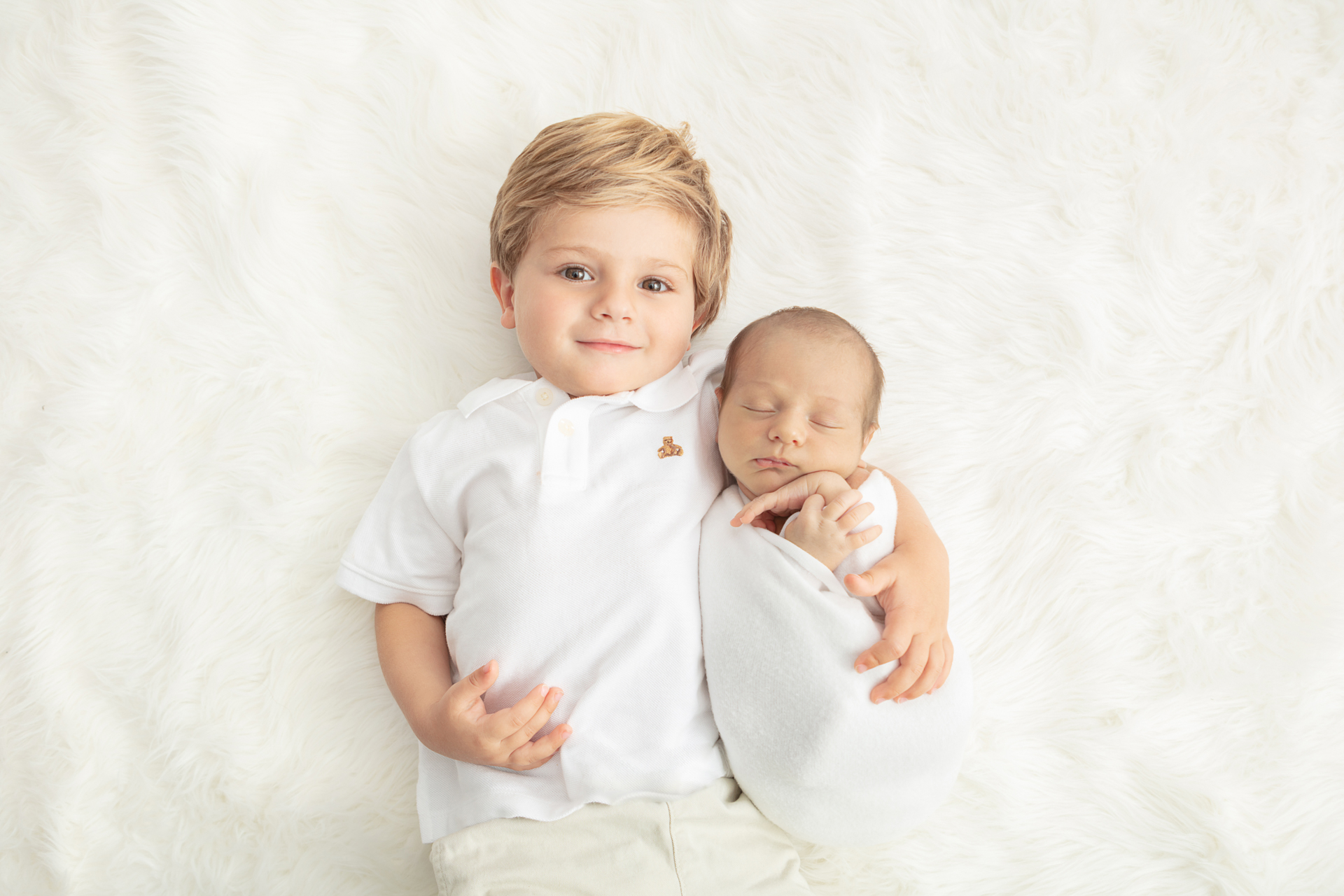 proud toddler brother with his arm around his new baby brother