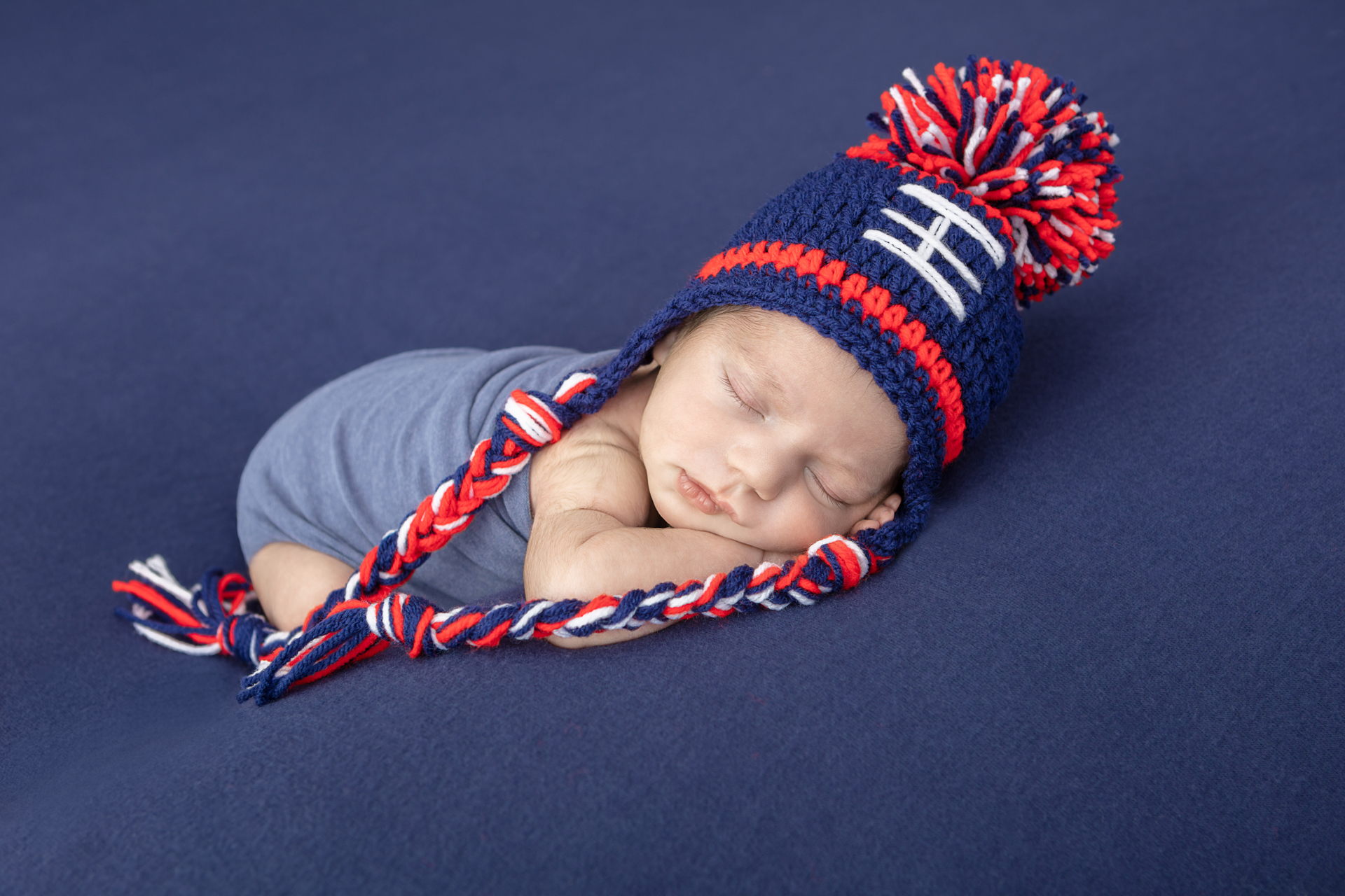 New England Patriots inspired newborn photo; sleeping baby boy wearing a Patriots red, white, blue stocking cap