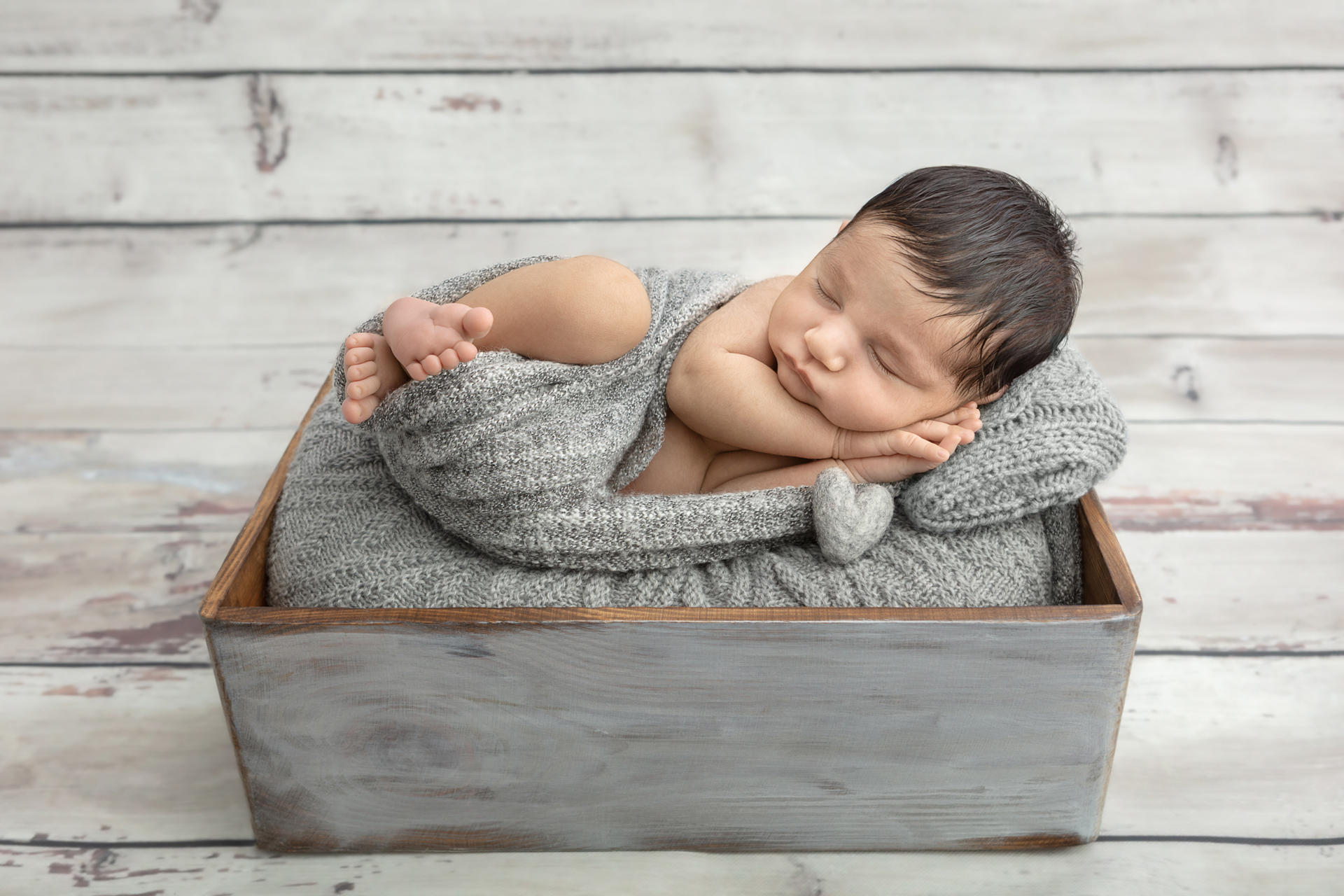 rustic newborn baby image with barn wood paneling backdrop; gray rustic box; gray heather swaddle