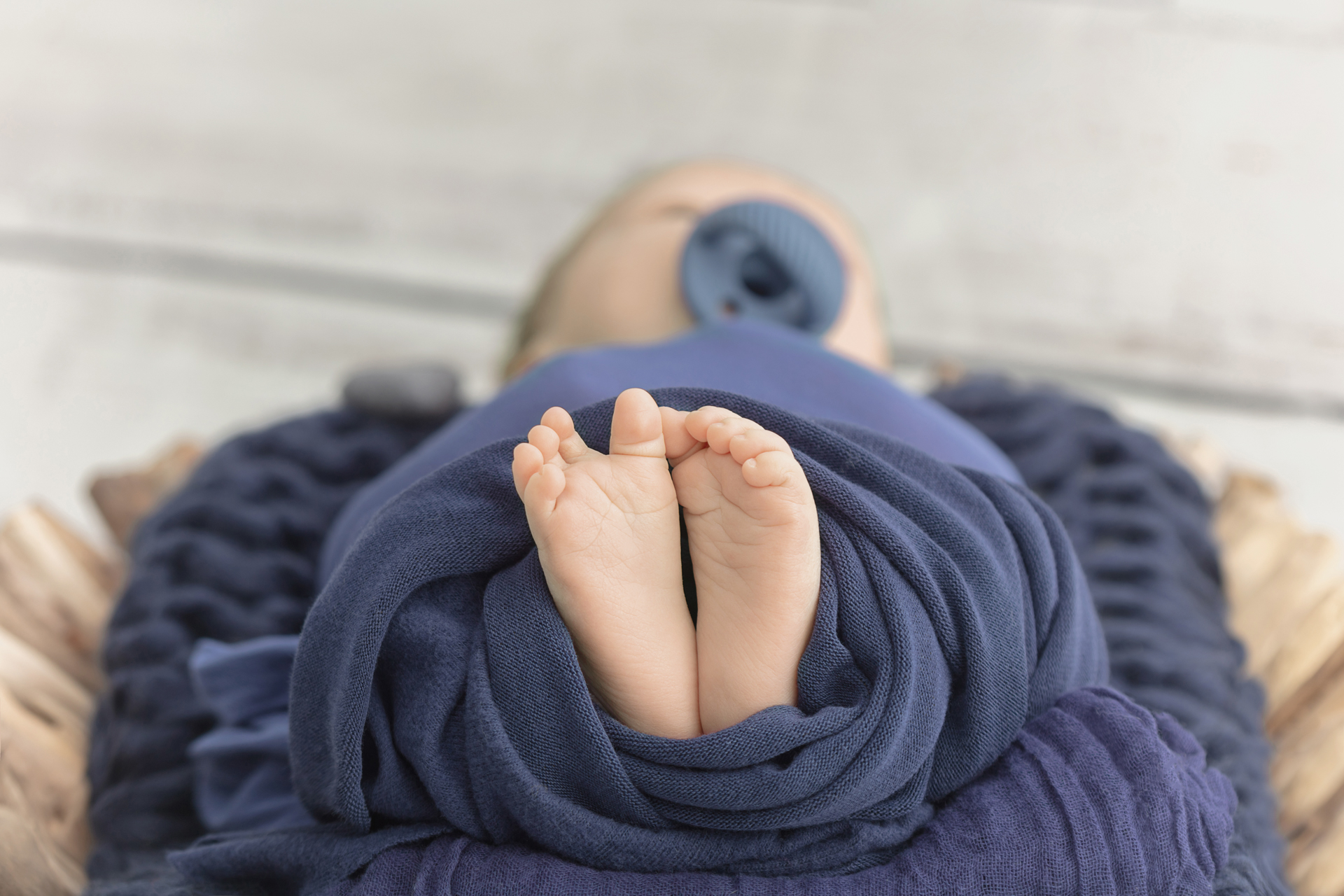 newborn baby feet and toes wrapped in a navy blanket and propped on navy muslin