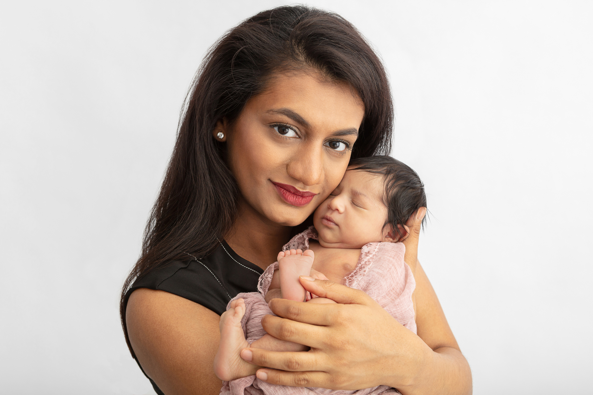 Indian mom holding her newborn daughter in her arms, holding her close to her face