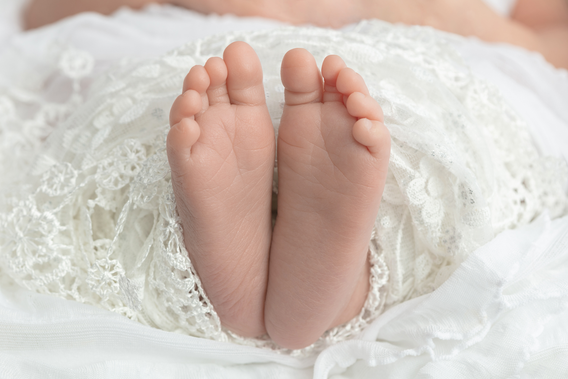 newborn baby feet with long toes peeking out of a lace blanket; Greenwich, Connecticut newborn photographer