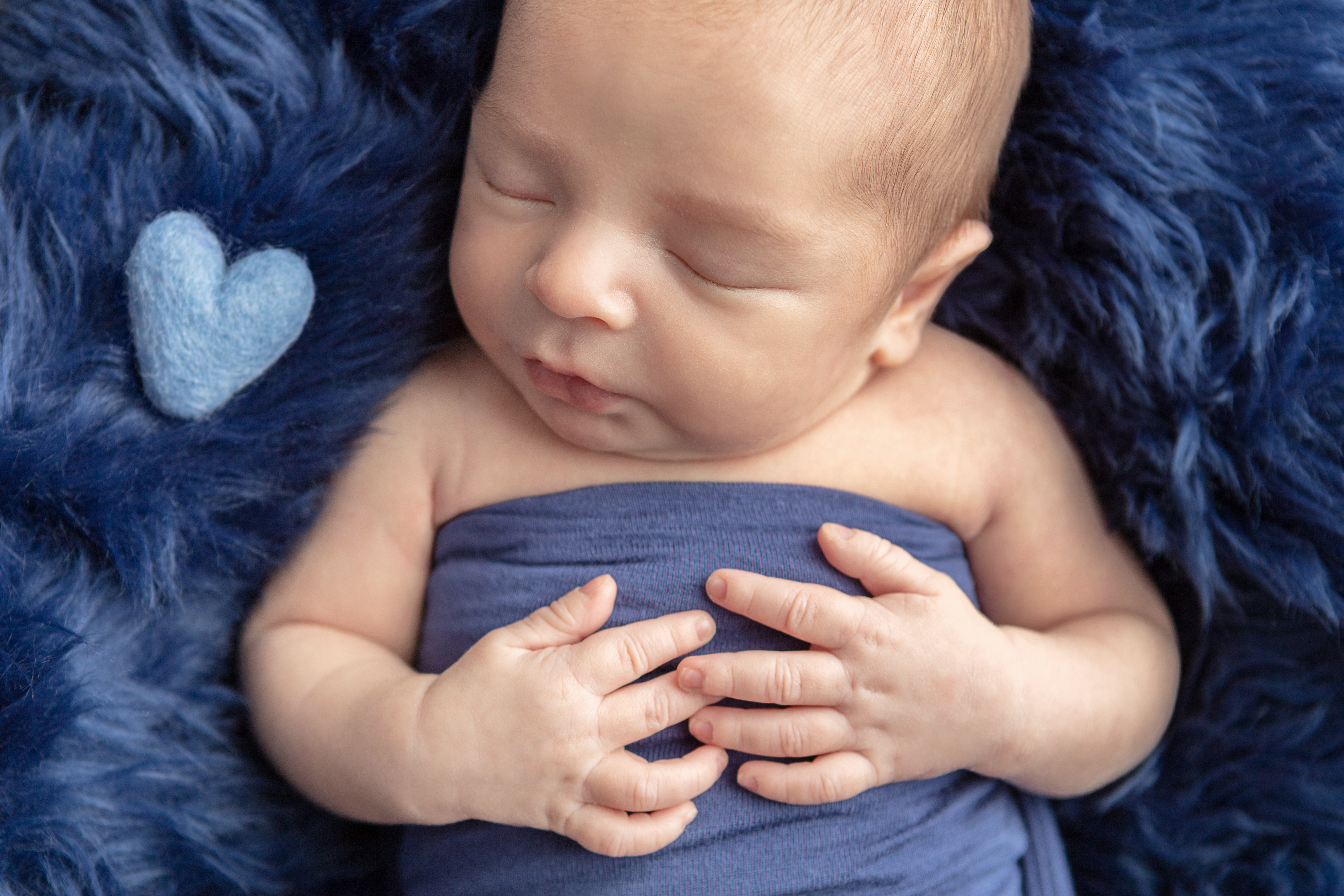 baby boy swaddled in blue asleep on a blue flokati