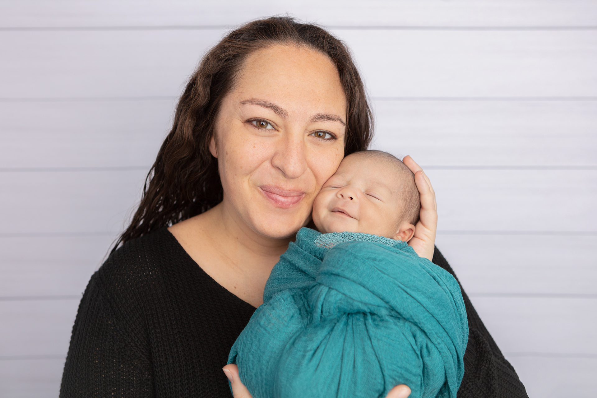 #smbc smiling and looking at the camera; smiling newborn baby boy being cradled by his mother