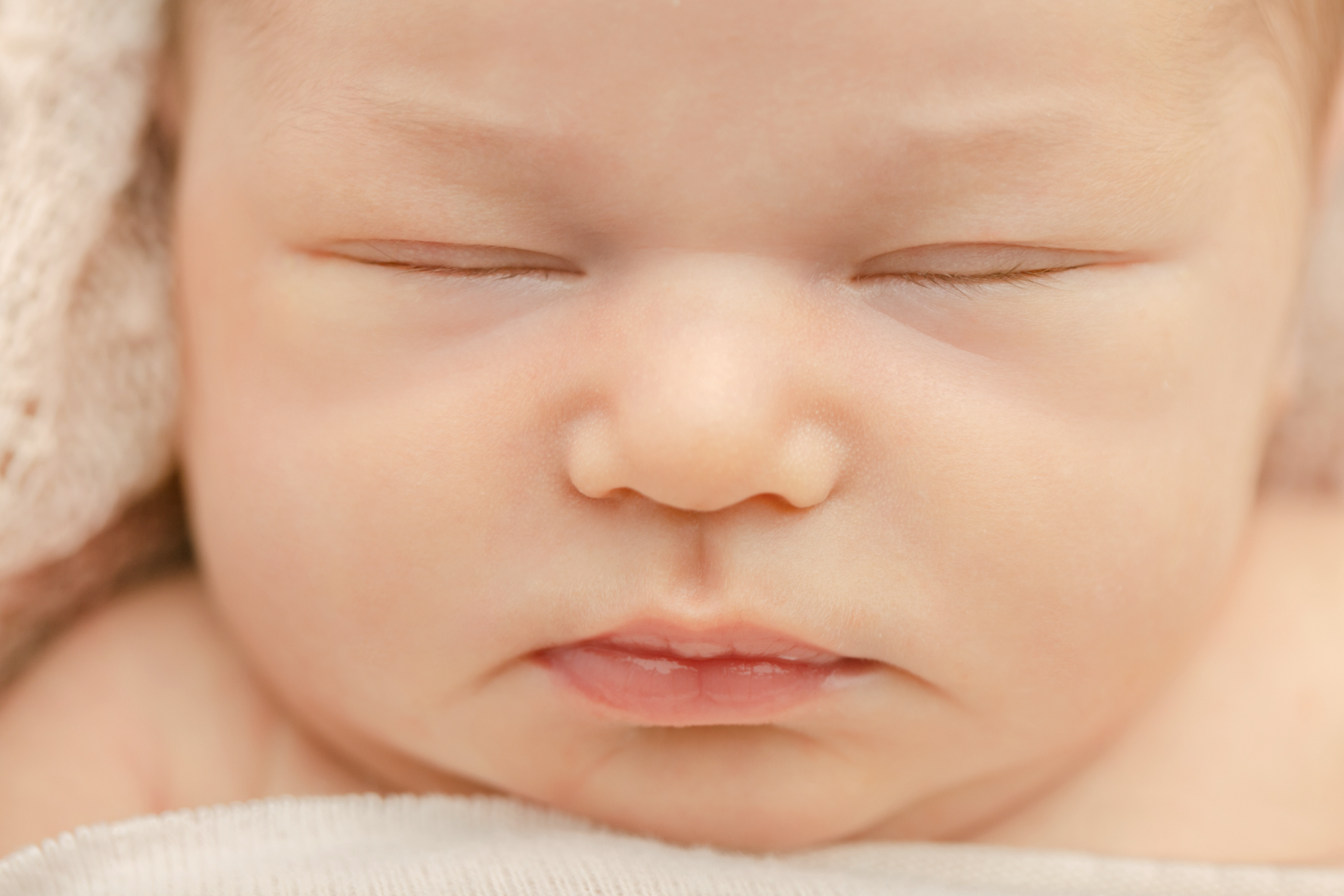 close-up pictures of a newborn baby girl's sleeping face with her eyes tightly shut