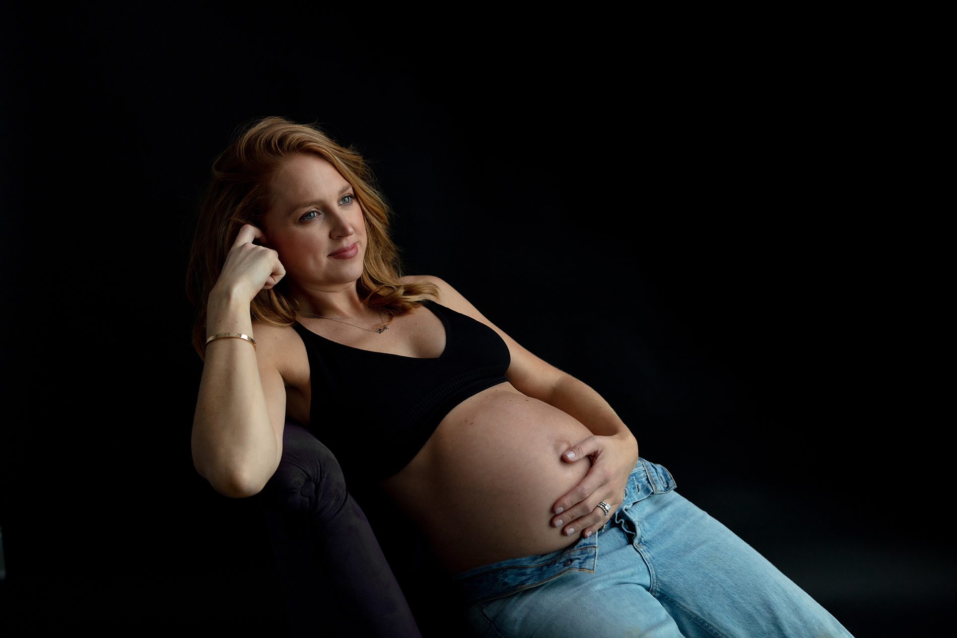 reclining pregnant mama with red hair, wearing jeans