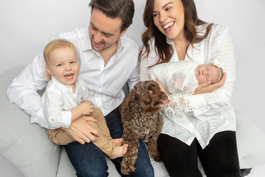 Newborn family portrait with dog inspiration. This family is photographed laughing, along with their newborn baby girl and their cockapoo, Mylo! Newborn family session with pet.
