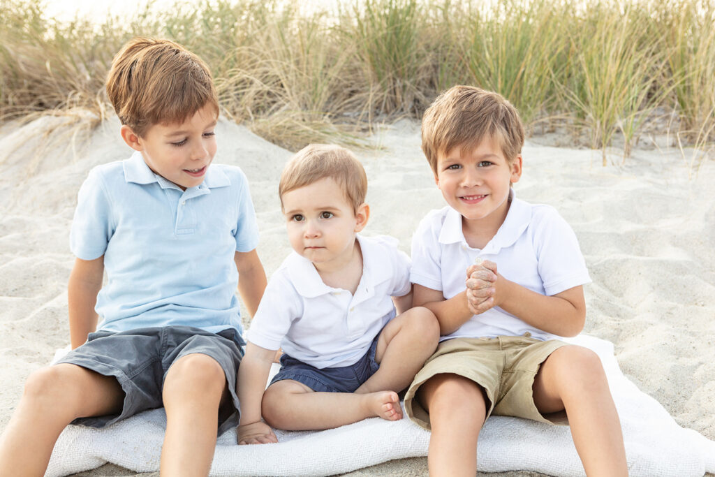 Three young, all-American boys sit in the sand at Greenwich Beach for a classic childhood portrait.
