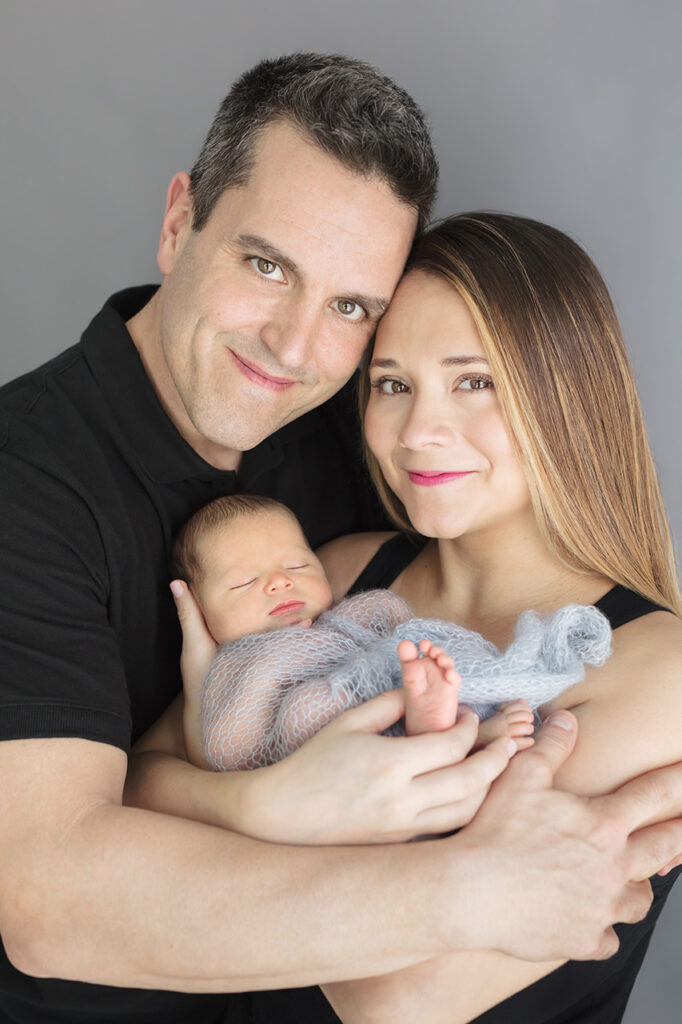 A studio family newborn session is captured by Karen Kahn, in her Greenwich, Connecticut photography studio. Proud new parents hold their newborn son.