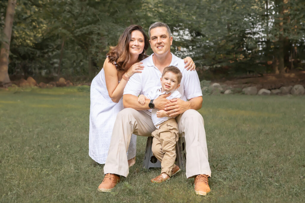 Autumn family portrait session in white and khaki. A family of three are photographed in a green space in Greenwich, Connecticut, looking like an all-American family.