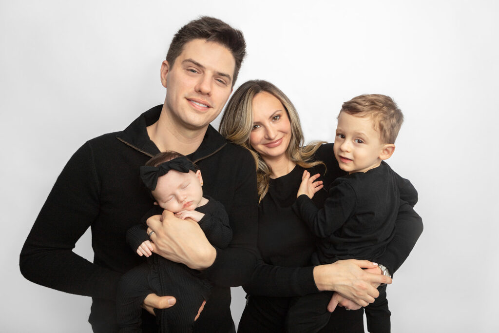 A new family of four is photographed in black, in the Looking Up Photography Studio, Greenwich, Connecticut. Photographed by Karen Kahn