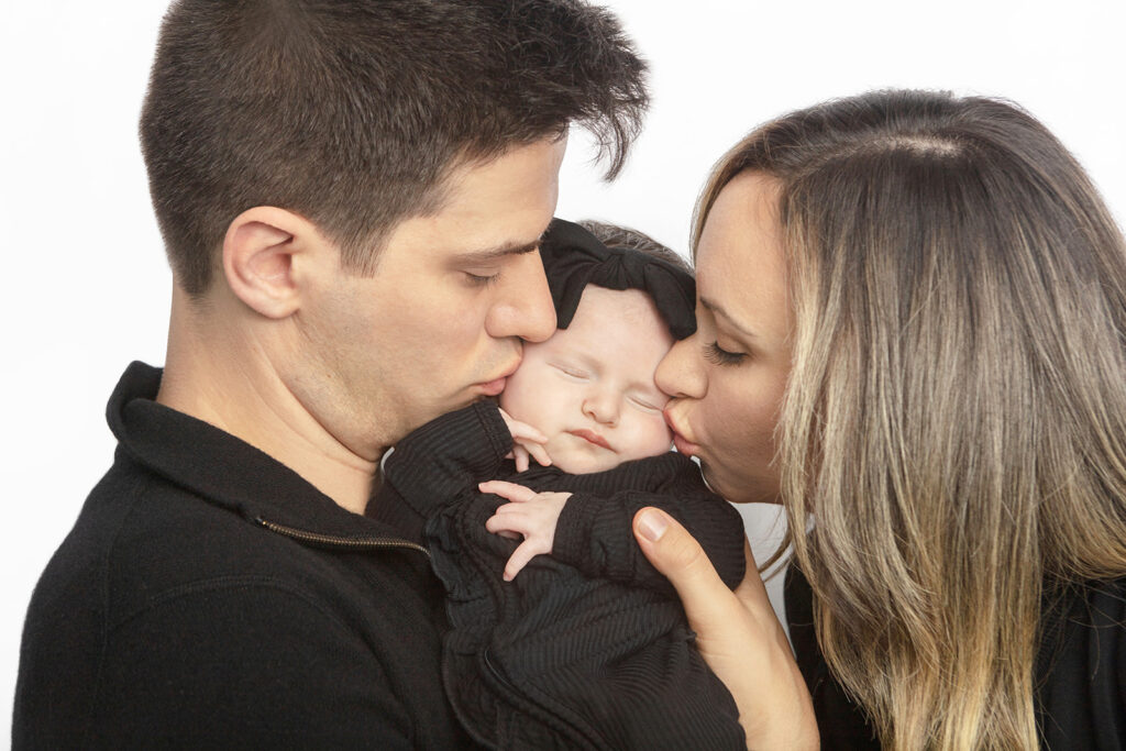 Father, mother, and newborn baby girl in black, photographed in the Looking Up Photography studio in Greenwich, Connecticut. Photographed by Karen Kahn