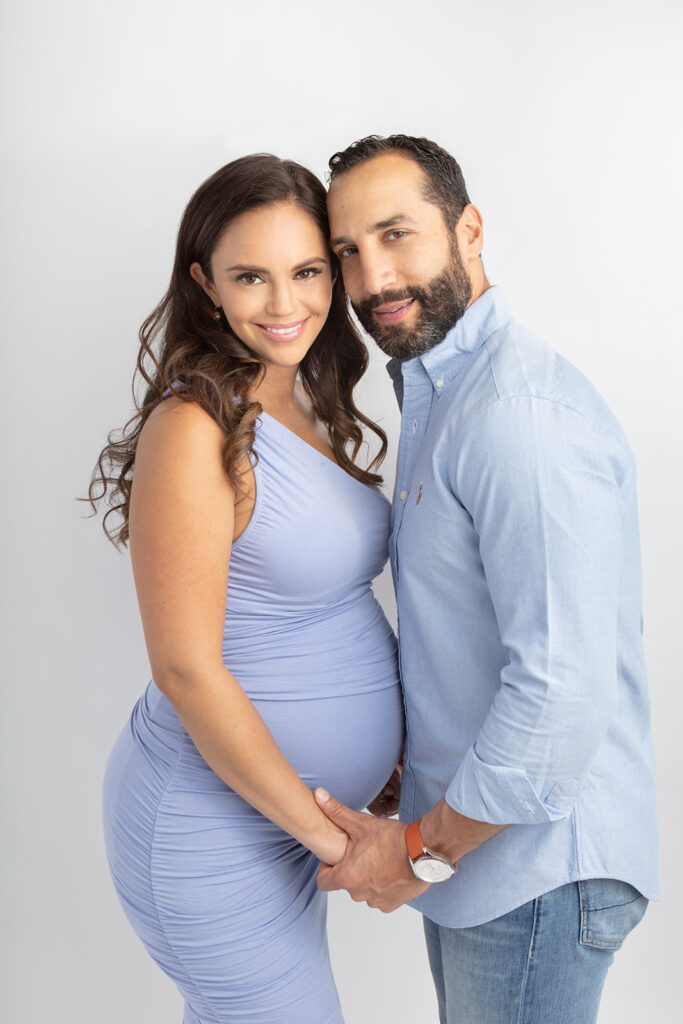 A beautiful, multicultural couple, are photographed for their maternity session inside the Looking Up Photography studio in Greenwich, Connecticut