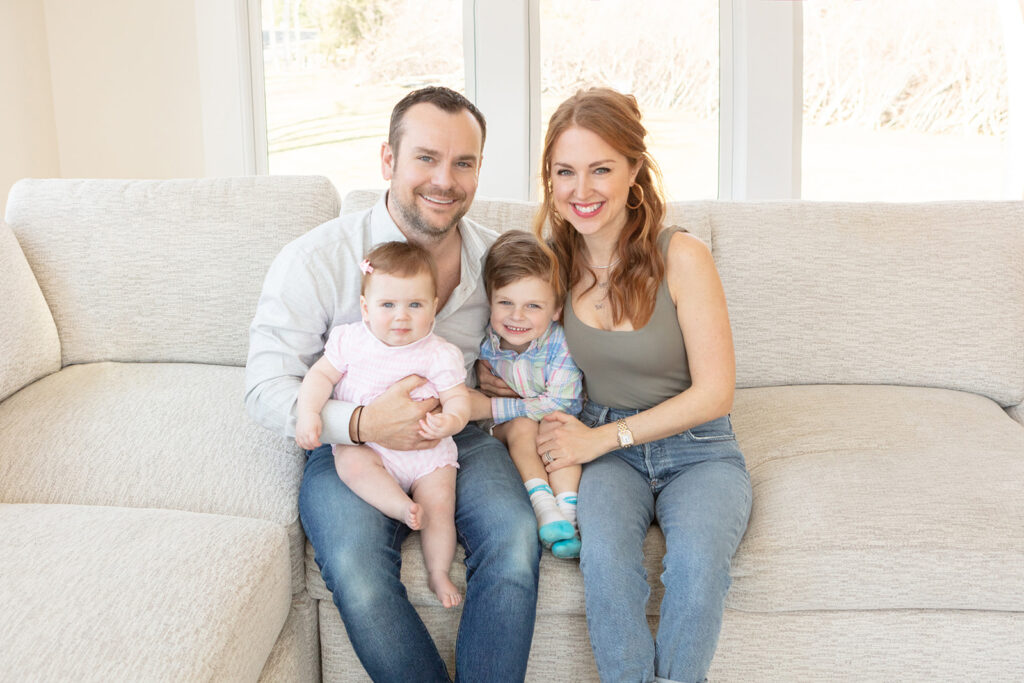 a Connecticut family of four sits on a styled, beige, textured couch in their Greenwich home, photographed by Karen Kahn of Looking Up Photography