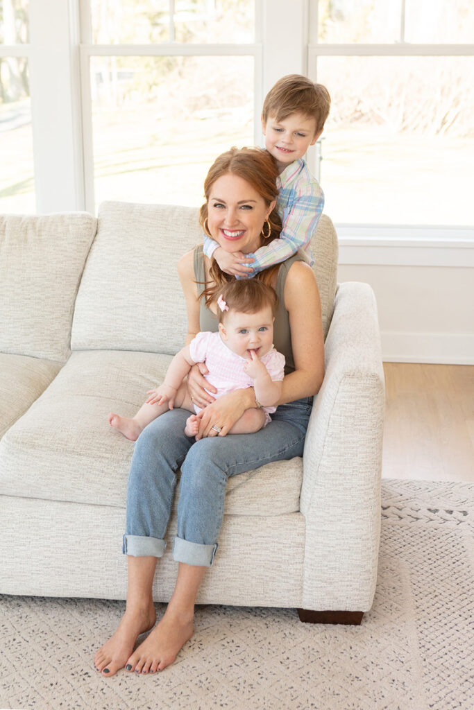 a smiling mom with vibrant red hair is photographed with her two young children, in her Connecticut home, styled by Cara Devine