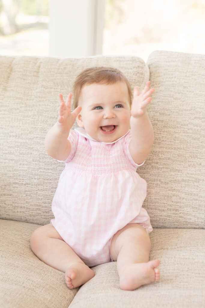 a 9-month-old little girl is photographed clapping her hands in mid-air for a milestone session in her family's home in Greenwich, Connecticut