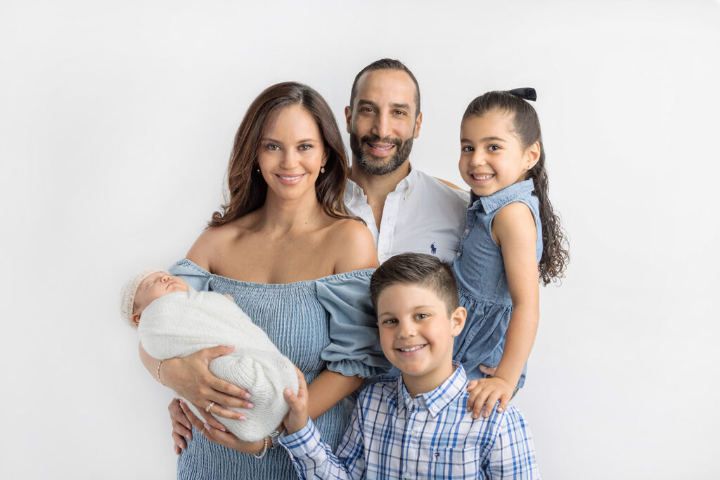 A new mom and dad, and their three children, are classically photographed inside the Looking Up Photography studio in Greenwich, Connecticut