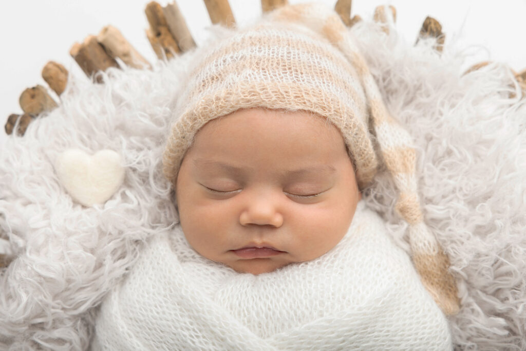 A close-up portrait of newborn baby Mateo snoozing in a driftwood basket at the Looking Up Photography studio in Greenwich, Connecticut, photographed by Karen Kahn