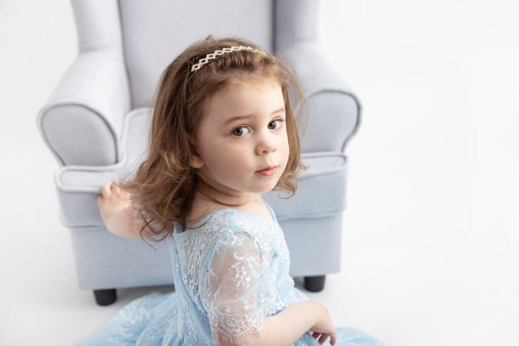 in her 3-year milestone portrait session, Blake turns and looks at the photographer over her shoulder, a serious and inquisitive expression on her face