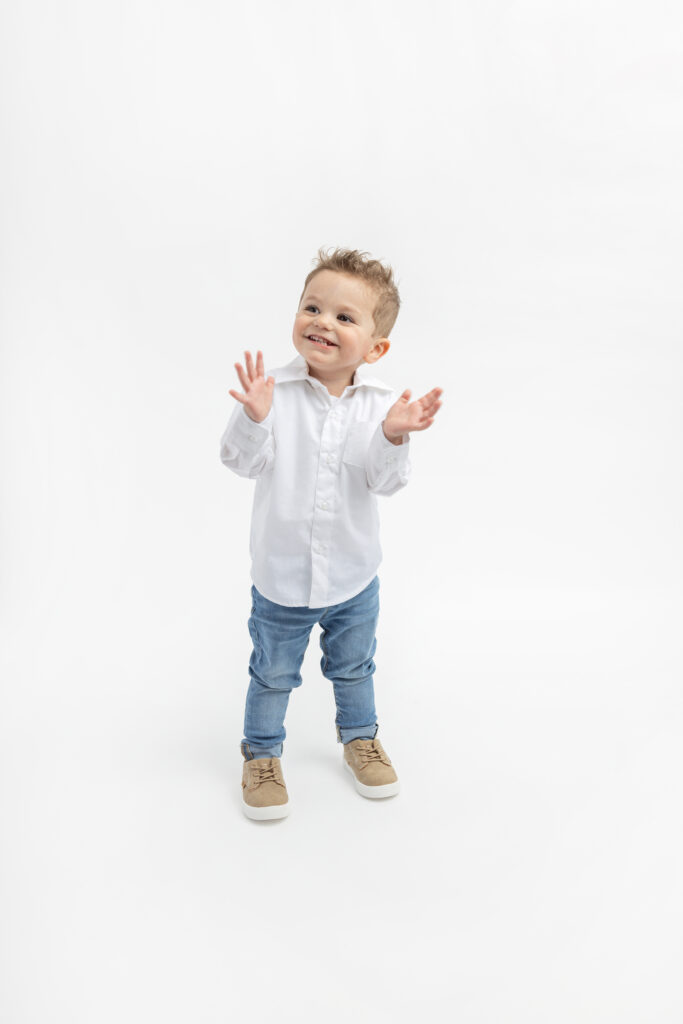 Classic toddler portrait inspiration. One and a half year old Cayden is photographed in a classic white Oxford, jeans, and Timberland-style sneakers, in the Looking Up Photography studio.