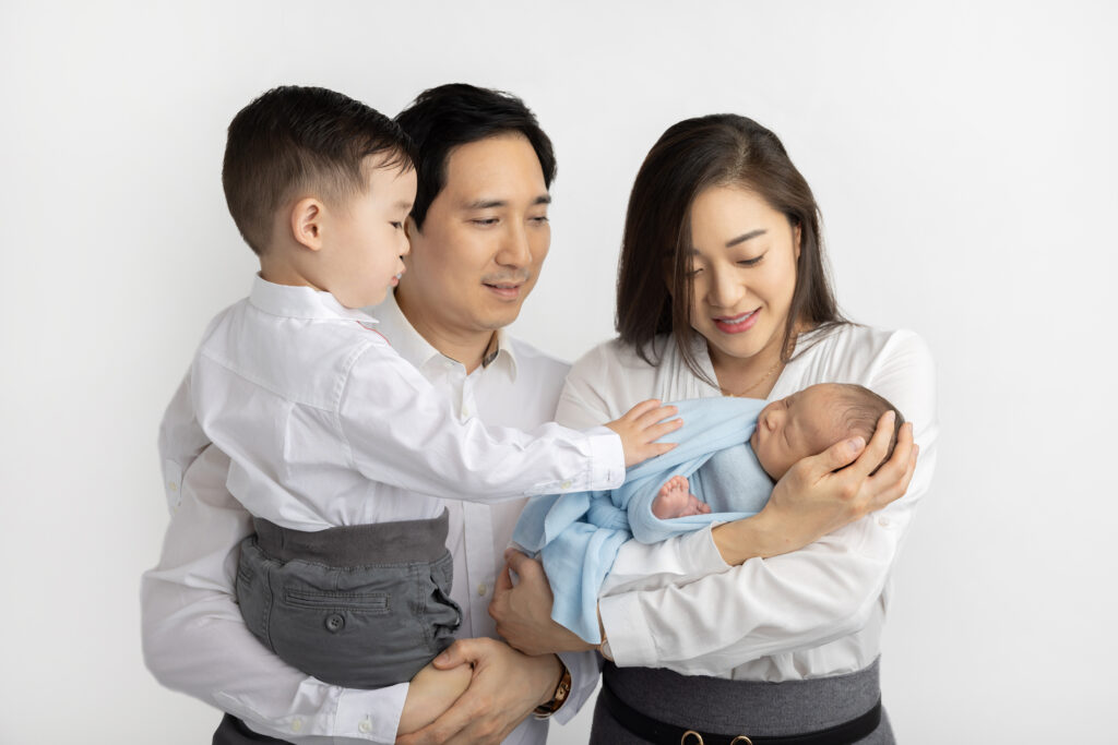 a growing family of four is photographed in the Looking Up Photography studio in Cos Cob, Greenwich, Connecticut, by Karen Kahn