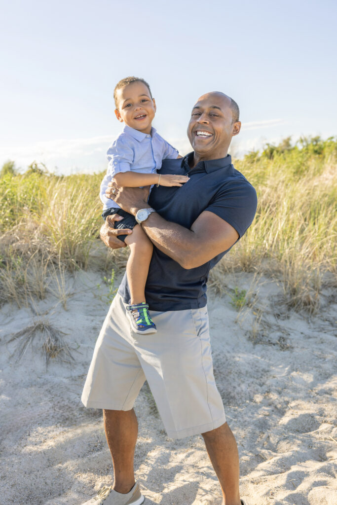 A father and his son are joyfully photographed against the backdrop of the Connecticut coastline, by Karen Kahn of Looking Up Photography, based in Greenwich, Connecticut.